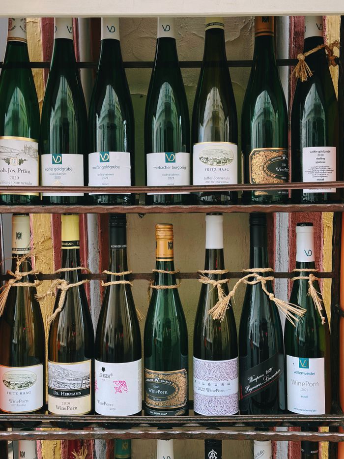 Variety of wine bottles elegantly arranged on a rustic wooden shelf.